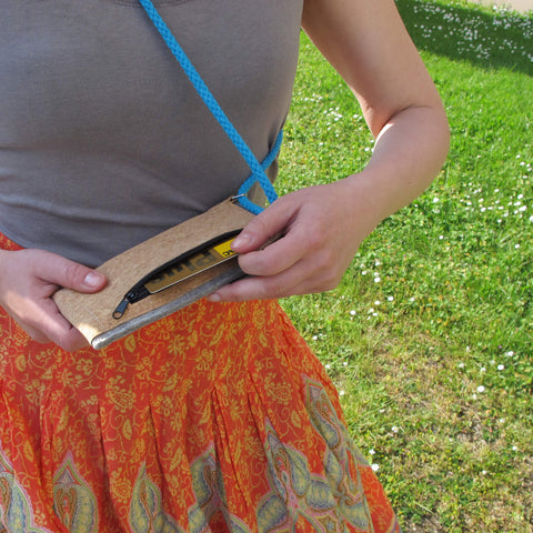 Person holding stylish Umhängetasche made of cork with adjustable strap outdoors.