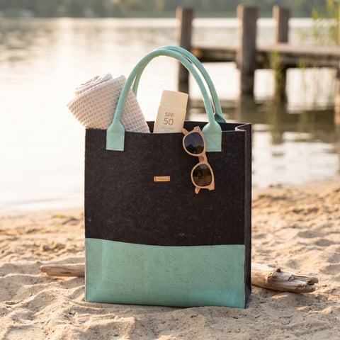 Dunkle Filz Shopper Tasche mit türkisfarbenem Korkboden am Strand, moderne nachhaltige Tasche mit stilvollem Design